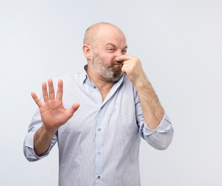 Man plugging his nose because of foul smelling sewer vent