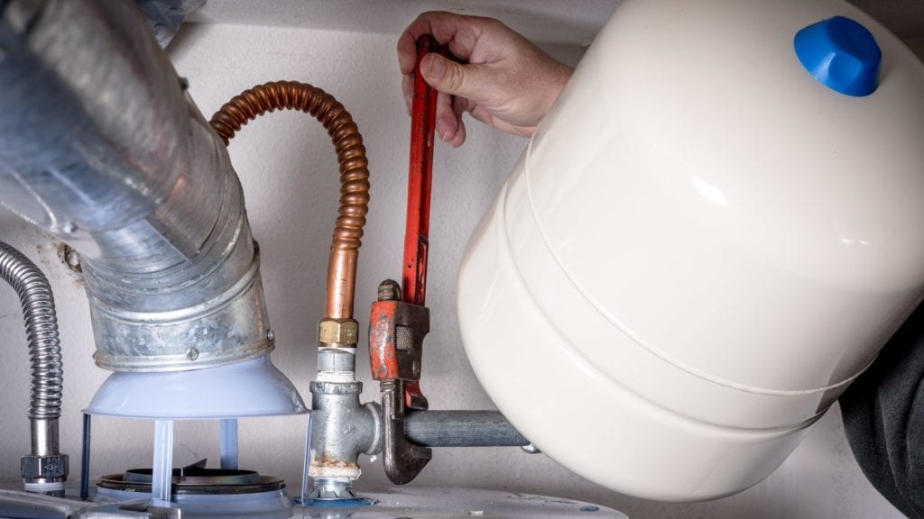 Plumber using a plumbing wrench to install a water heater