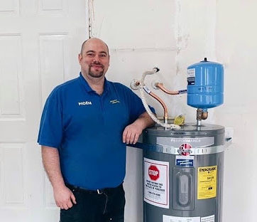 Simpson Plumbing tech standing next to a water heater to help illustrate water heater leak.